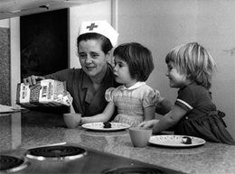 A Red Cross nurse feeding two children during the First World War