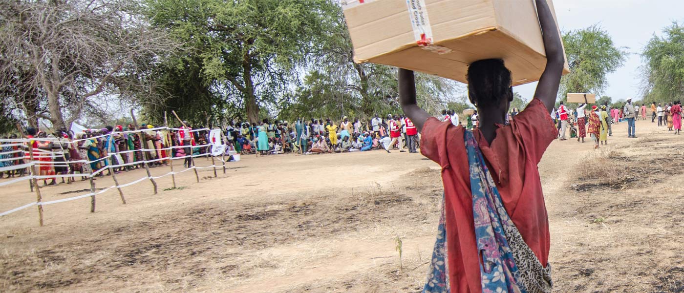 Une femme reçoit des semences et des outils dans un centre de distribution de la Croix-Rouge.