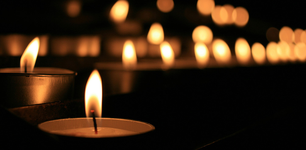 Tealight candles burn in darkness.