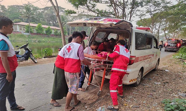 Red Cross volunteers are loading a stretcher into a Red Cross van.