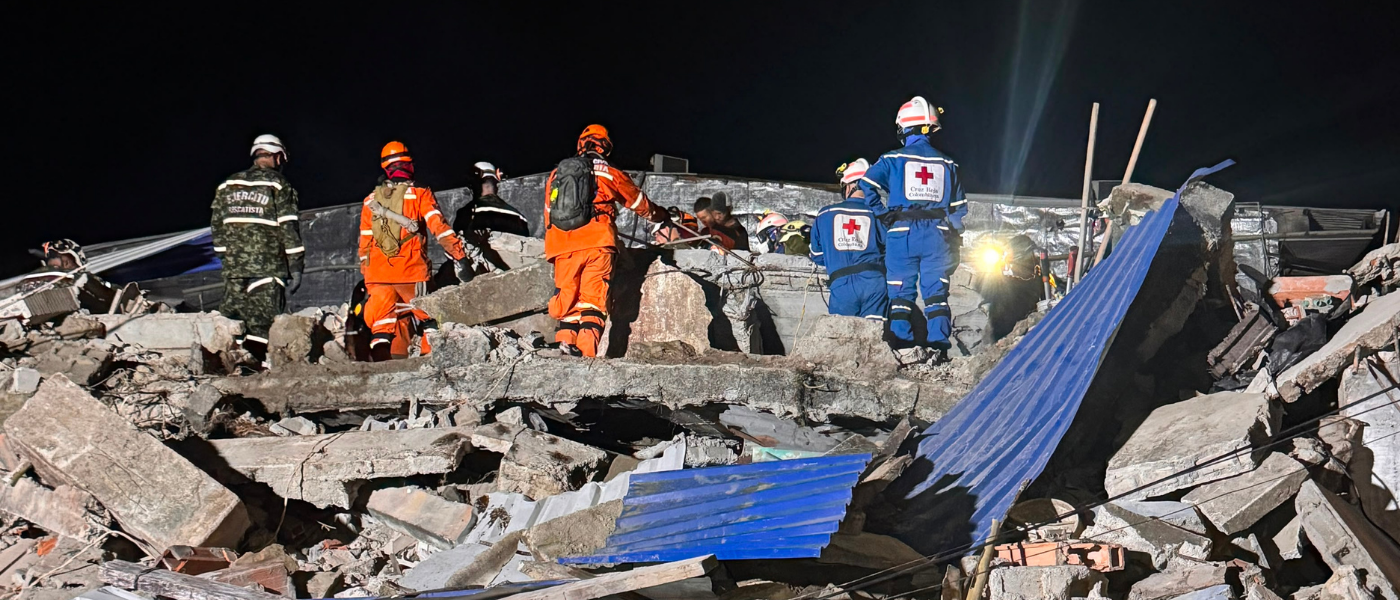 Des membres du personnel de la Croix-Rouge colombienne fouillent les décombres aux côtés d'autres secouristes pendant la nuit. 