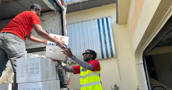 Des membres du personnel de la Croix-Rouge de la Jamaïque déchargent des boites d’un camion.