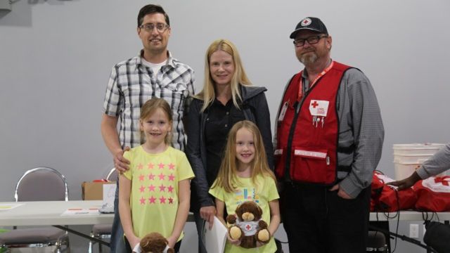 Une famille à côté d'un homme du CRC dans un centre de lutte contre les incendies de l'Alberta
