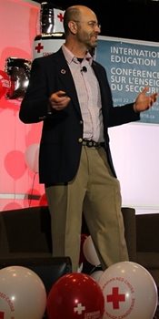 Dr. Jeff Pellegrino standing by Canadian Red Cross balloons at a podium.