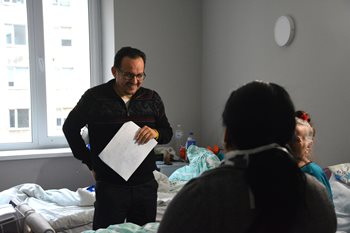 Le docteur Oleh Berezyuk discute avec des patients, tout en souriant, une feuille de papier dans sa main gauche