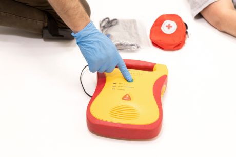 A person is using an AED by pressing the button during first aid and CPR training.