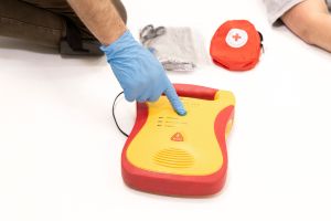 A person is using an AED by pressing the button during first aid and CPR training.