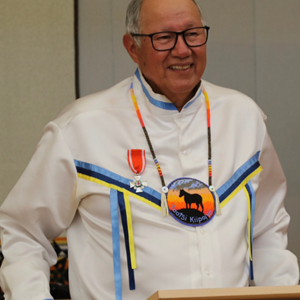 A man stands behind a podium, smiling whiling giving a speech at the Order of the Red Cross ceremony.