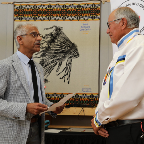 A man presents an Order of the Red Cross award to an honoured recipient.