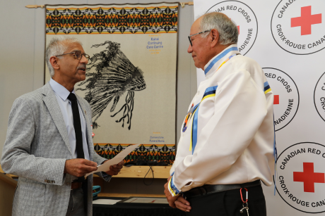 A man presents an Order of the Red Cross award to an honoured recipient.
