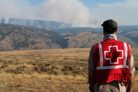 A Red Cross Personnel looking at smoke from the 2021 British Columbia wildfires at a distance. 
