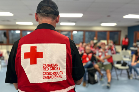 Canadian Red Cross Personnel standing back on, speaking to a group of people