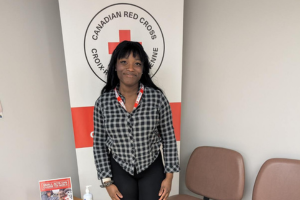 Laura Enekegho poses in front of a Canadian Red Cross banner.