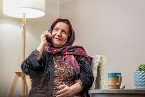 A woman smiles while holding a cellphone to her ear