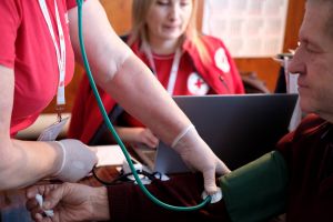 Ukrainian Red Cross Society personnel taking the blood pressure of a person at a Mobile Health Unit.