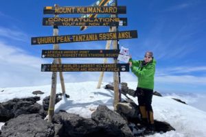 Linda Phillips holds a Canadian Red Cross and Tiffany Circle flag at the top of Mount Kilimanjaro.