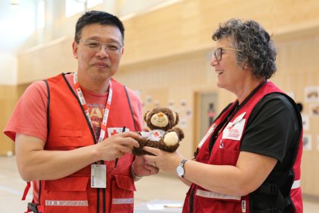 Deux bénévoles de la Croix-Rouge canadienne portant des gilets de la Croix-Rouge et tenant un ours en pleuche.