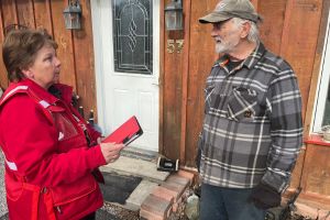Une bénévole de la Croix-Rouge canadienne s’entretient avec un résident à l’extérieur de son logement.