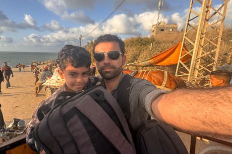 Amr et son fils tenant un sac à dos avec une plage en arrière-plan.