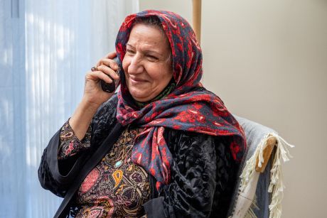 Une personne assise sur une chaise, souriant au téléphone.