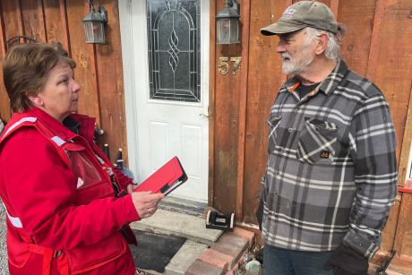 A Canadian Red Cross volunteer speaking with a resident outside of a home.