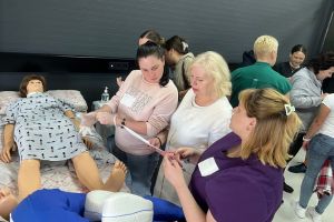 A group of nurses taking part in training, standing beside a medical manikin.