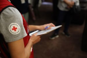 Une personne portant un t-shirt de la Croix-Rouge canadienne et tenant un stylo et une planchette à pince.
