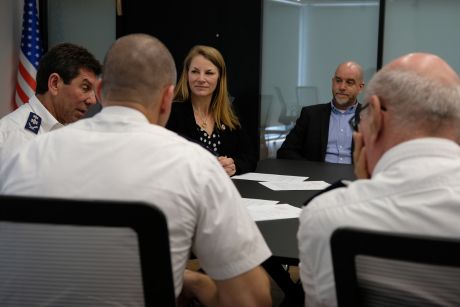 Kelsey Lemon and four other people seated around a table in a board room. 