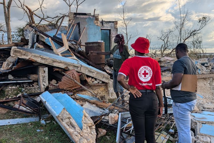 Jamaica Red Cross personnel stand in front of debris and damage from Hurricane Melissa.
