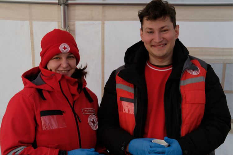 Ukrainian Red Cross Society personnel serve hot cups of tea and coffee.