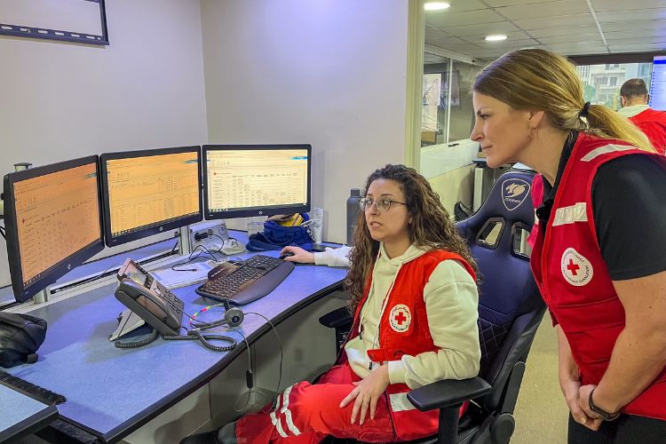 Two people observing computer screens in an emergency medical services dispatch centre.