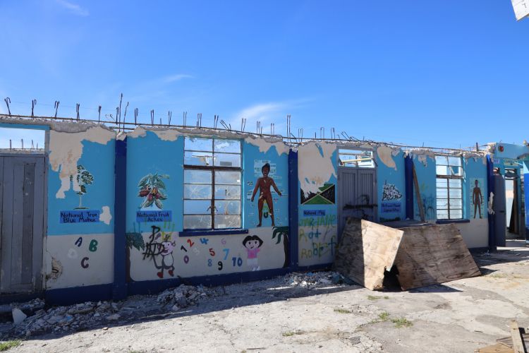 Damaged school building with no roof, featuring colourful walls with numbers, letters, and cartoon characters painted on them.