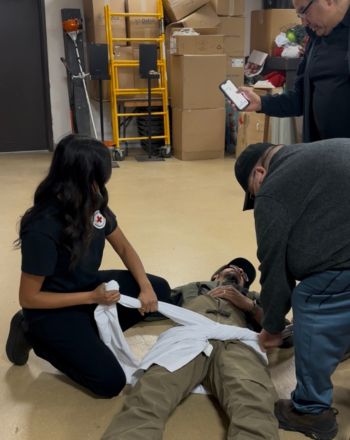Trois personnes prodiguent les premiers soins à une personne étendue par terre dans le cadre d’une simulation.