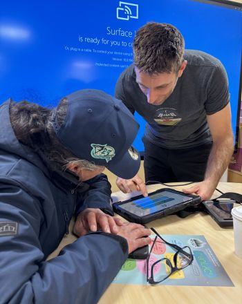 Deux personnes utilisent le manuel de secourisme conçu pour les trappeurs cris sur une tablette.