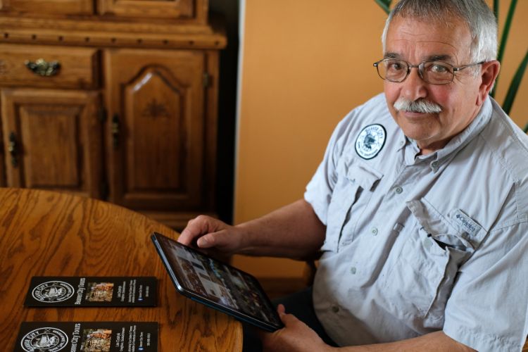 A person sitting at a kitchen table, holding a tablet.