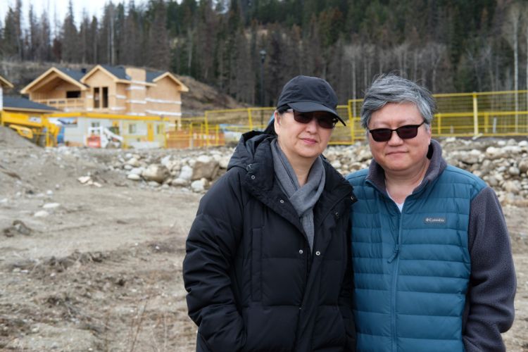 Deux personnes côte à côte posent avec, en arrière-plan, un chantier de construction.