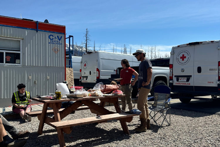 Red Cross personnel gather around a picnic table.
