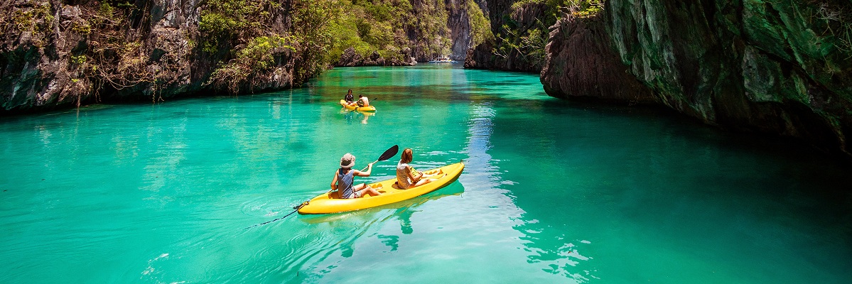 Two people rowing a boat together in a scenic, picturesque location surrounded by nature.