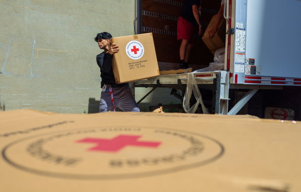 A volunteer transporting a box with the Canadian Red Cross logo
