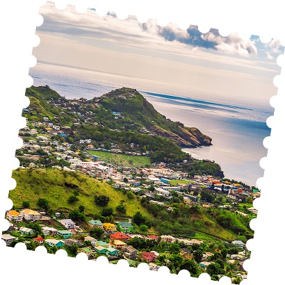 Colorful houses nestled in a green coastal town, beside a calm ocean.