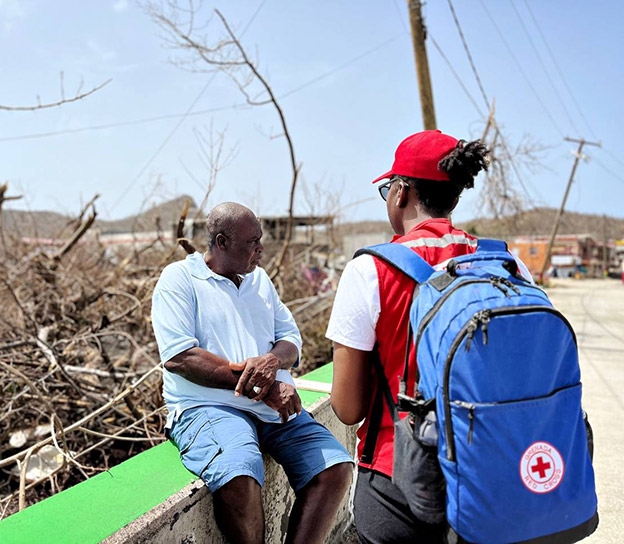 A Red Cross member speaks with a man in Jamaica amidst the destruction of Hurricane Beryl. 