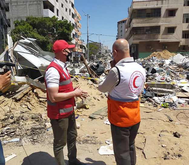 Members of the Red Crescent stand in front of bombed buildings in Gaza.