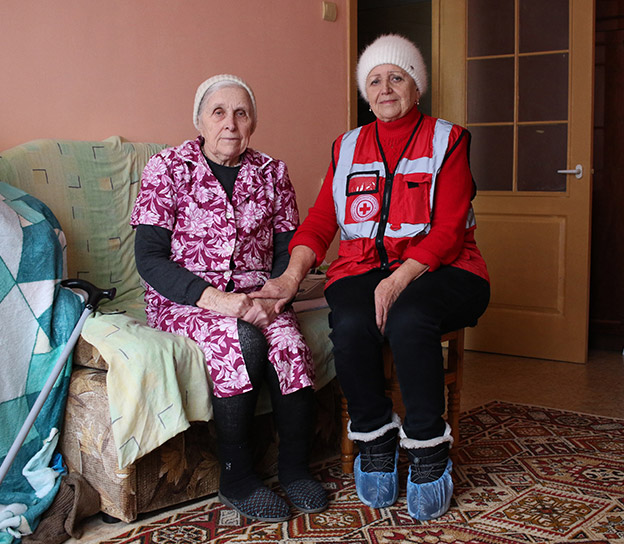 A member of the Red Cross sits with an elderly woman in Ukraine.