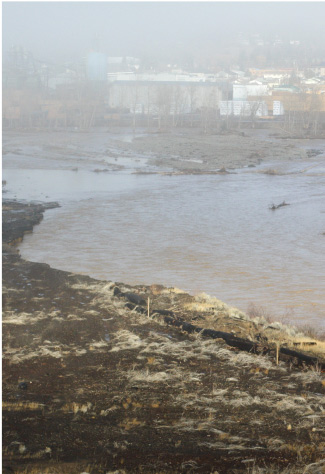 A murky river in BC, showcasing muddy waters due to flooding conditions from recent storms.