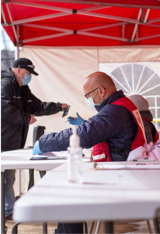 A man in a red vest provides support at a table for those affected by the Fort McMurray Floods.