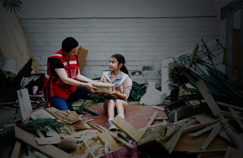 Canadian Red Cross volunteer helping young girl after a hurricane.