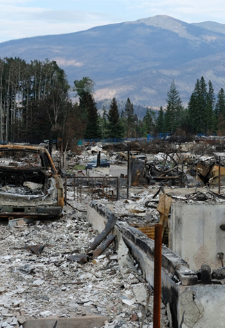 A burnt car sits amongst debris from a destroyed building after wildfires in Jasper.