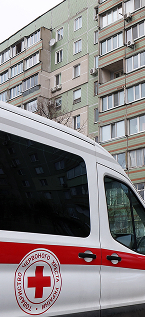 A white vehicle in front of a building, representing emergency response amid the ongoing humanitarian crisis in Ukraine. 