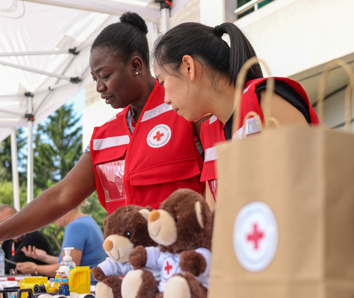Canadian Red Cross personnel standing with teddy bears and supplies