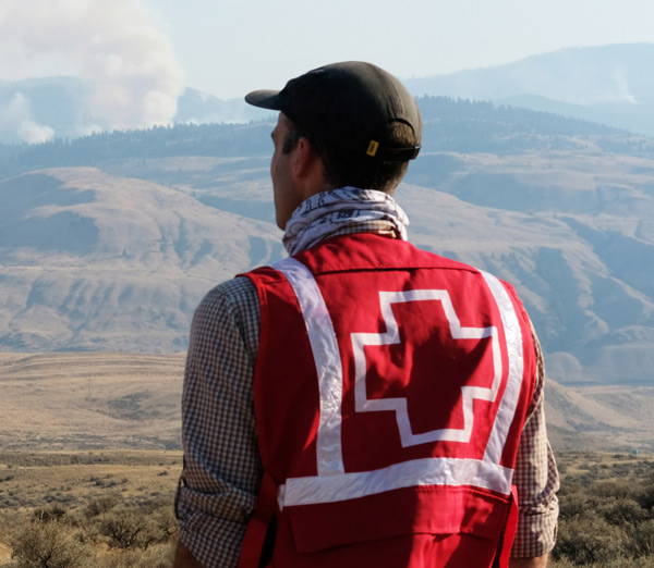 Une personne portant une veste de la Croix-Rouge regarde les montagnes.